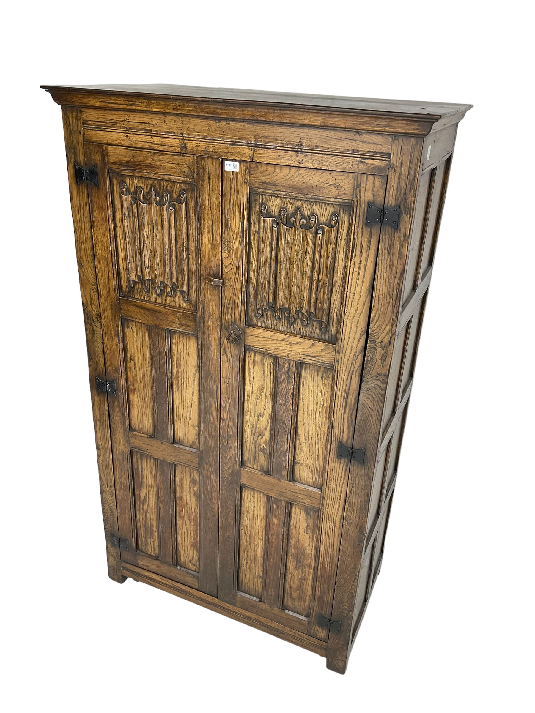 Mid-to-late 20th century oak double wardrobe, enclosed by panelled doors with linenfold decoration