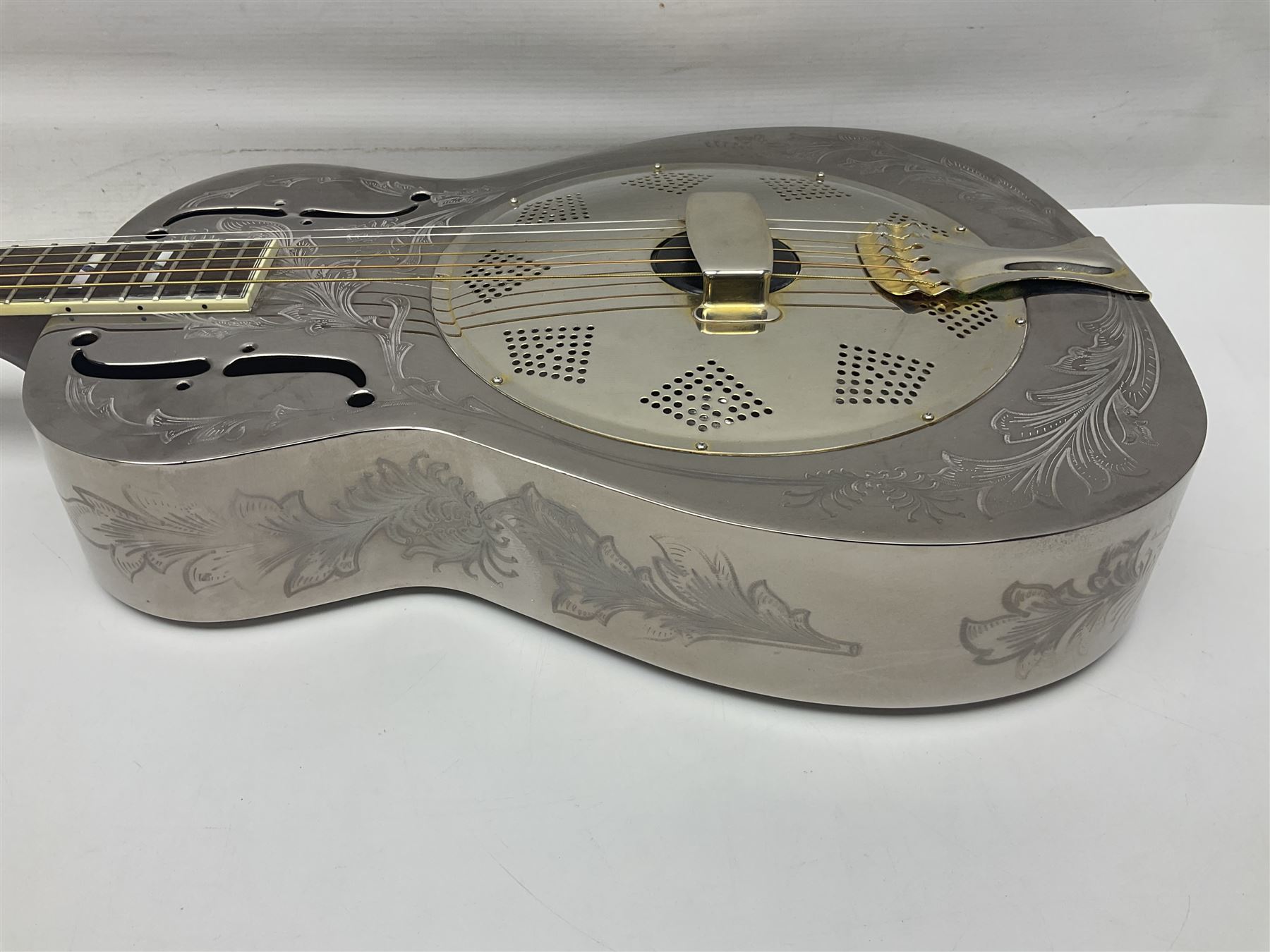 Ozark metal cased resonator guitar with all over chased foliate decoration to the polished finish and mother-of-pearl inlay to the fretboard L100cm; in Stagg hard carrying case