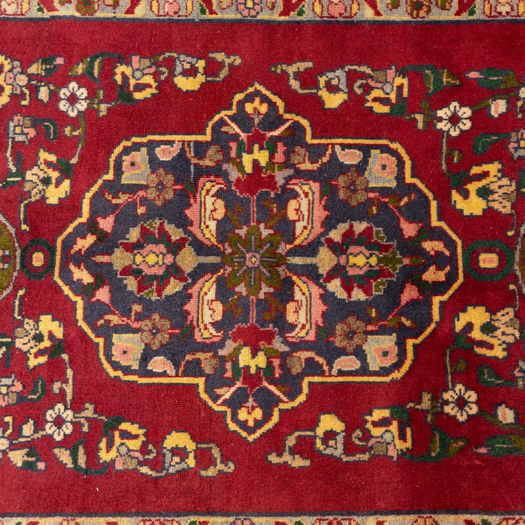 North West Persian Tariz hand-knotted runner, madder red field with a column of linked lozenge medallions in shades of indigo blue and pistachio green framed by stylized floral motifs within triple borders of rosettes and scrolling vines on an ivory ground, with cotton fringe ends