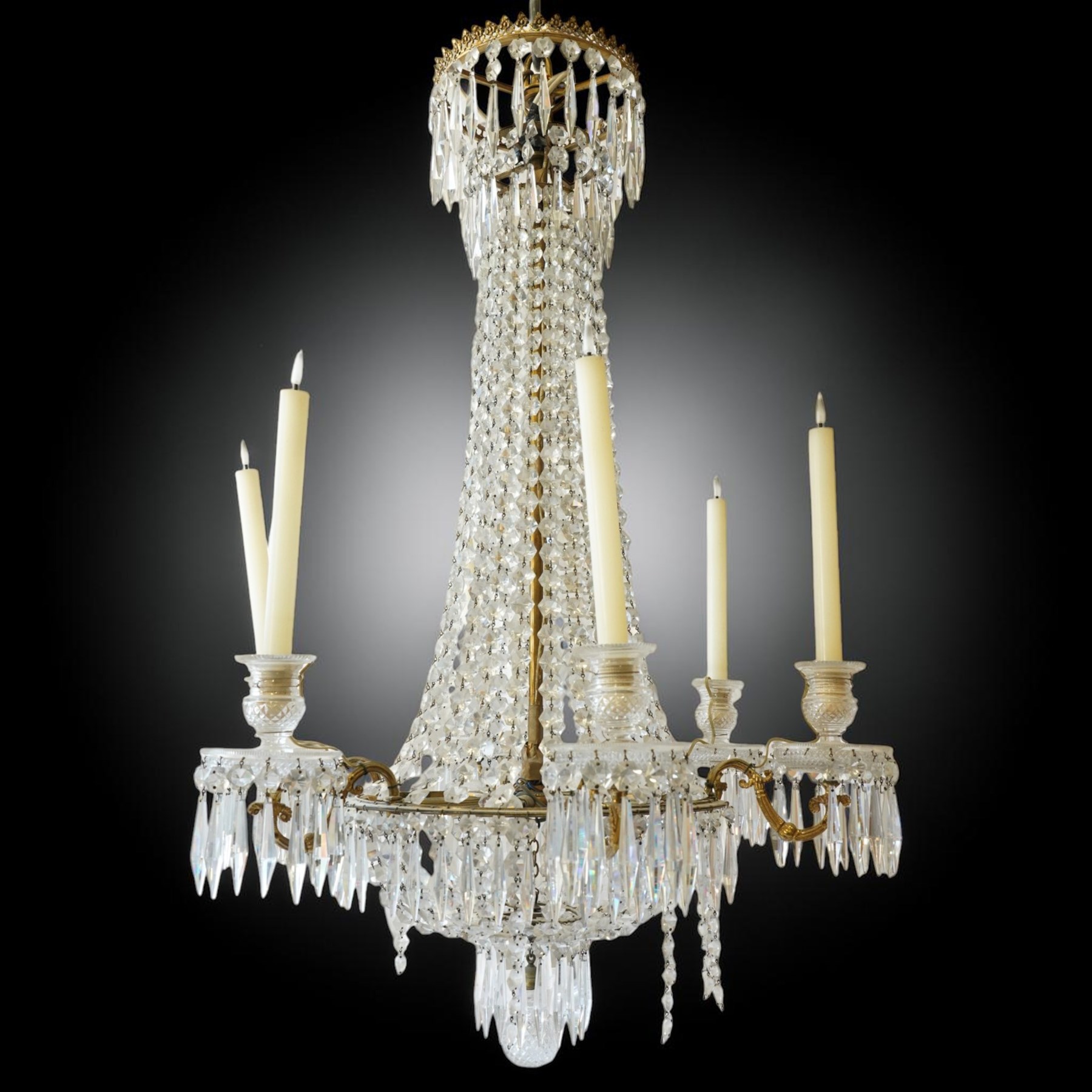 Regency Country House cut-glass and ormolu six light chandelier, the outer shaft with ormolu foliate moulding hung with octagonal and drop pendants, the impressive central shaft with cascading drops of cut-glass, the scroll branches with hob-nail cut candle holders and wax pans, with central similarly cut terminal
Provenance: property of a nobleman