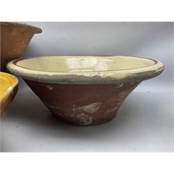 Six late 19th century terracotta bread pancheons, the bowls with glazed interiors, largest pancheon D50cm