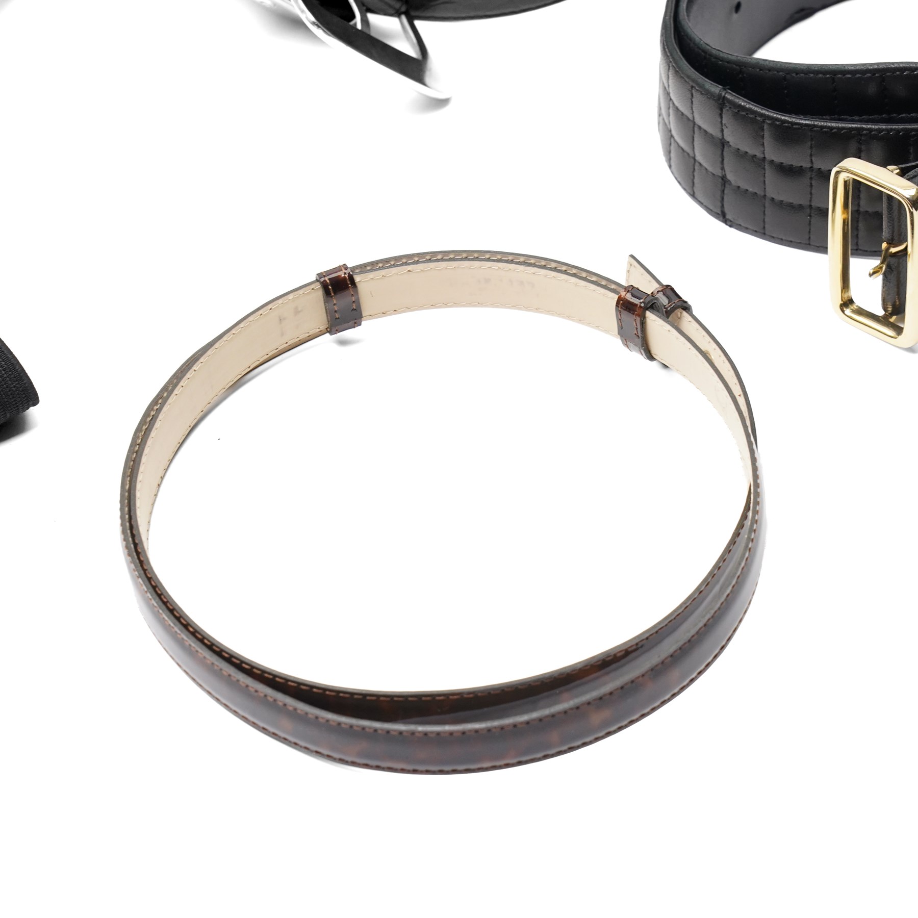 Collection of belts, including white Nike Golf leather belt with oval green and silver Nike swoosh buckle, white Nike leather belt in perforated pattern, black Aigner crocodile-embossed leather belt with large gold buckle, black Jaeger quilted leather belt with rectangular gold buckle, etc (10)