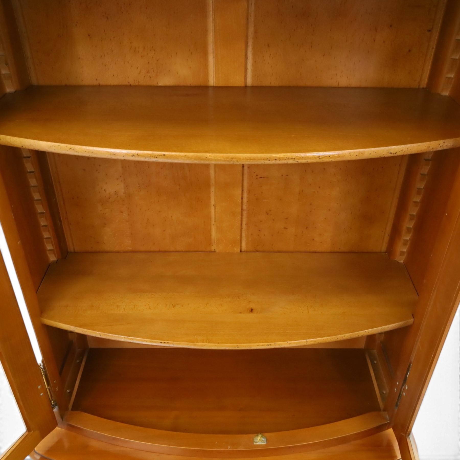 Wesley Barrell - French cherry wood bow front display cabinet, the upper section with glazed doors and three adjustable shelves, raised on cupboard base with brushing slide and further adjustable shelf, raised on a moulded plinth base with bracket feet