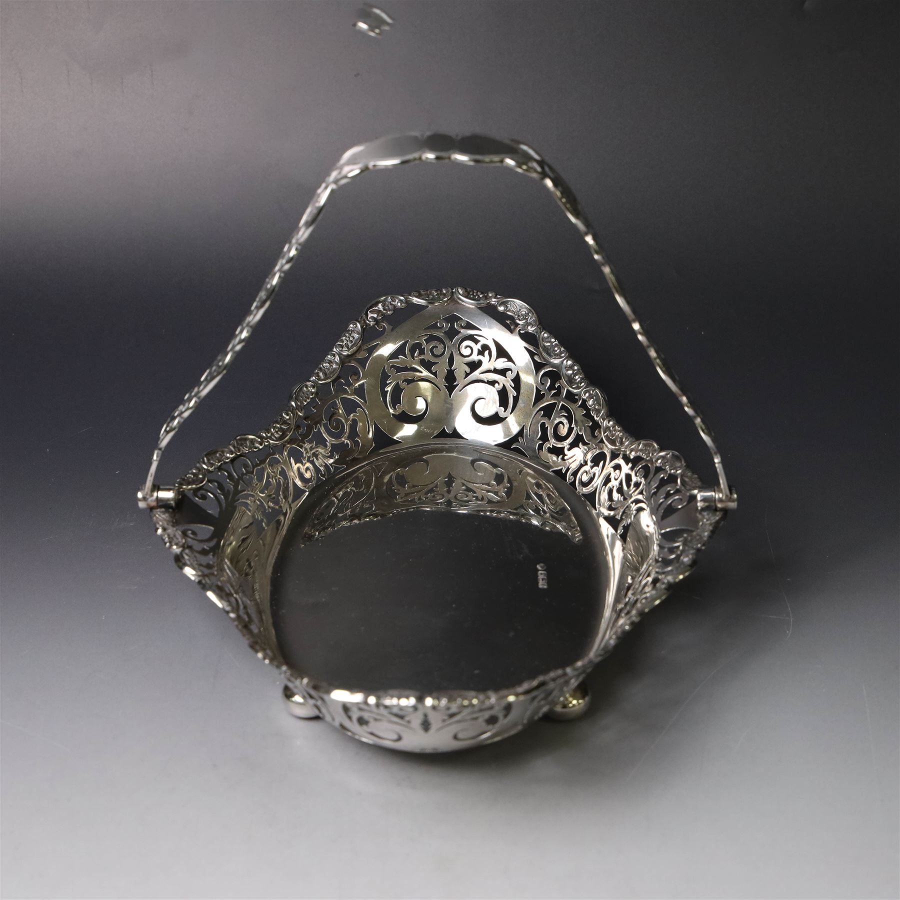 Early 20th century swing handled basket, of oval form with pierced sides and floral C scroll rim, upon four bun feet, hallmarked William Hutton & Sons Ltd, Sheffield 1915, widest point W29cm