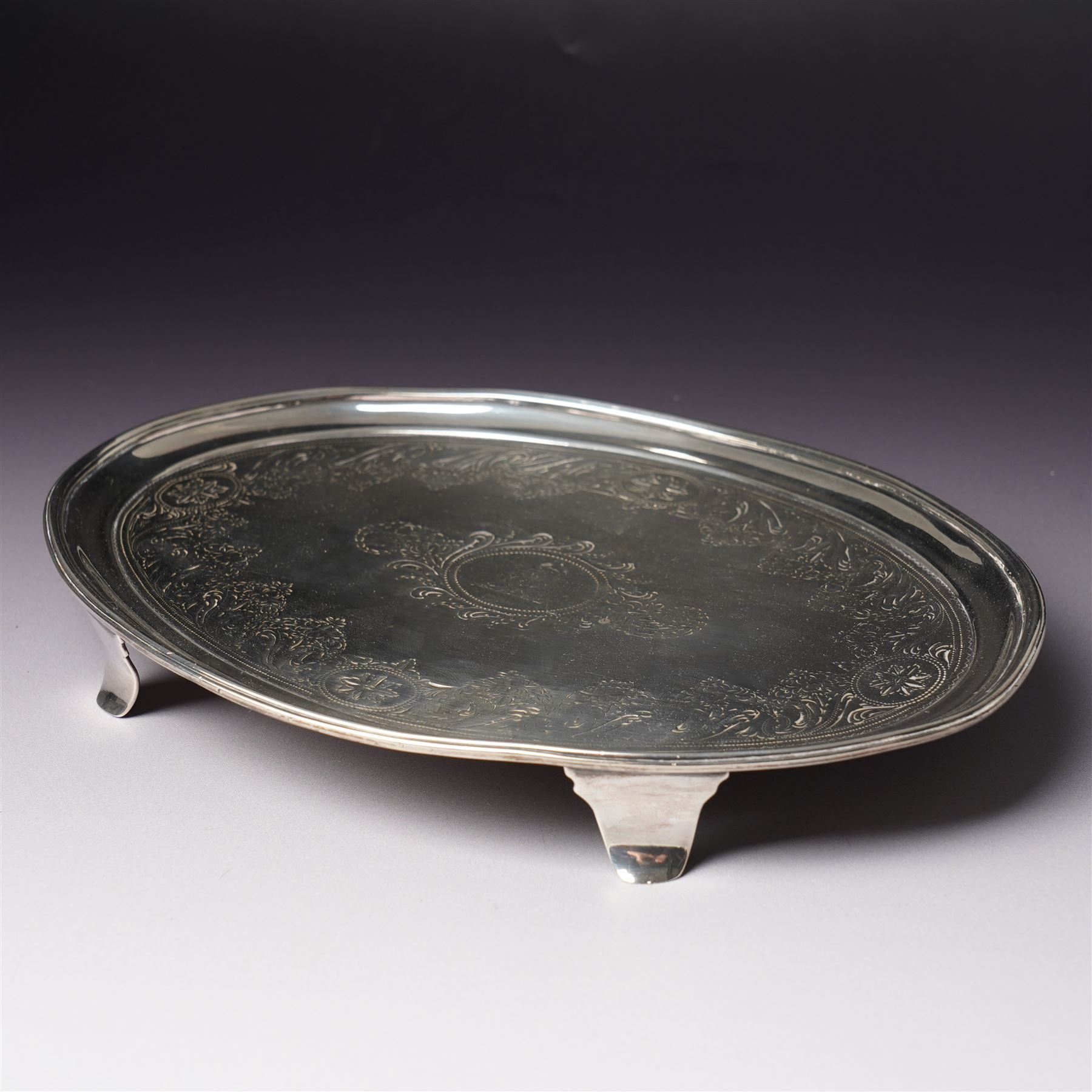 George III Irish silver oval teapot stand engraved with garlands scrolls and central crest on shaped supports L20cm Dublin 1802 Maker possibly Richard Sawyer
