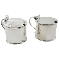 Two early 20th century silver mustard pot and covers, each of plain drum form, the first example with domed cover, hallmarked Reid & Sons, London 1927, the second with scroll handle, hallmarked Crichton Brothers, London 1935, each with blue glass liner, each approximately H6cm, approximate total silver weight 5.98 ozt (186.2 grams)