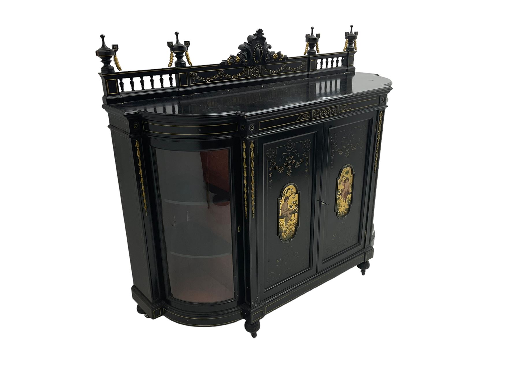 Victorian ebonised credenza side cabinet, raised balustrade back with urn finials and a central carved cartouche, carved and gilded with floral garland decoration, central doors with gilt panels painted with figures sitting over a lake enclosing two shelves, flanked by applied bellflower detail and glazed bow-front side doors, raised on ring turned feet with castors