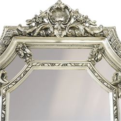 Impressive Baroque Revival mirror in antique silvered finish, the pierced cartouche shell pediment flanked  by C-scrolls and flower heads, the outer frame with ribbon-twist motifs throughout, the central arched bevelled plate surrounded by further rectangular mirror panels with cartouche mounts
