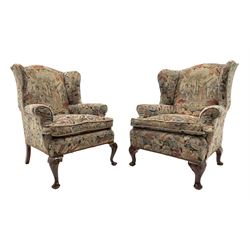 Matched pair early 20th century Queen Anne style wingback armchairs, walnut framed, sprung seats with seat cushions upholstered in needle work cover, shell carved cabriole front feet