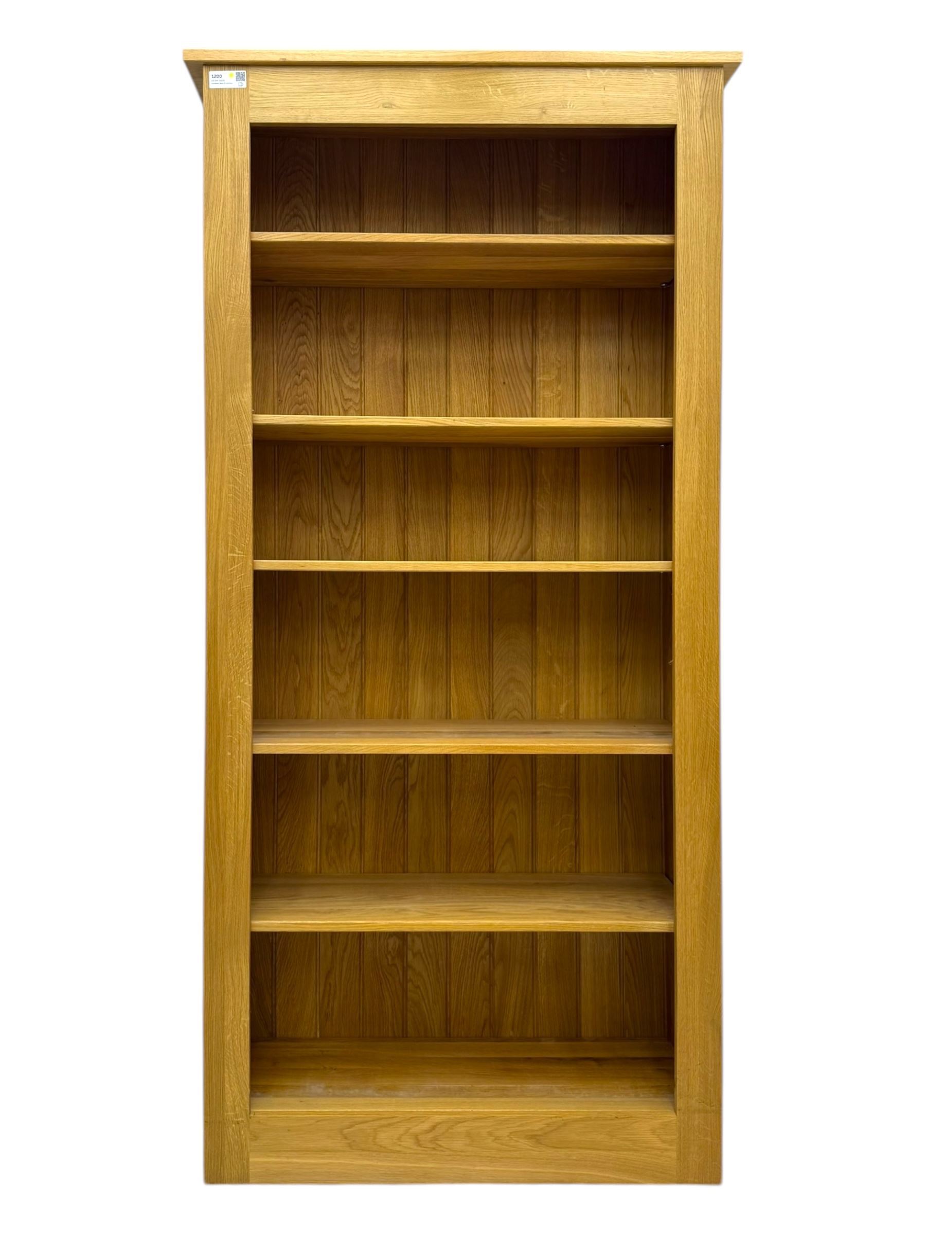 Contemporary light oak open bookcase, rectangular form with projecting top, fitted with five adjustable shelves, on a straight plinth base