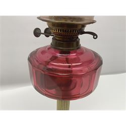 Victorian oil lamp, with brass corinthian column, cranberry glass reservoir and stepped ceramic base, H66cm