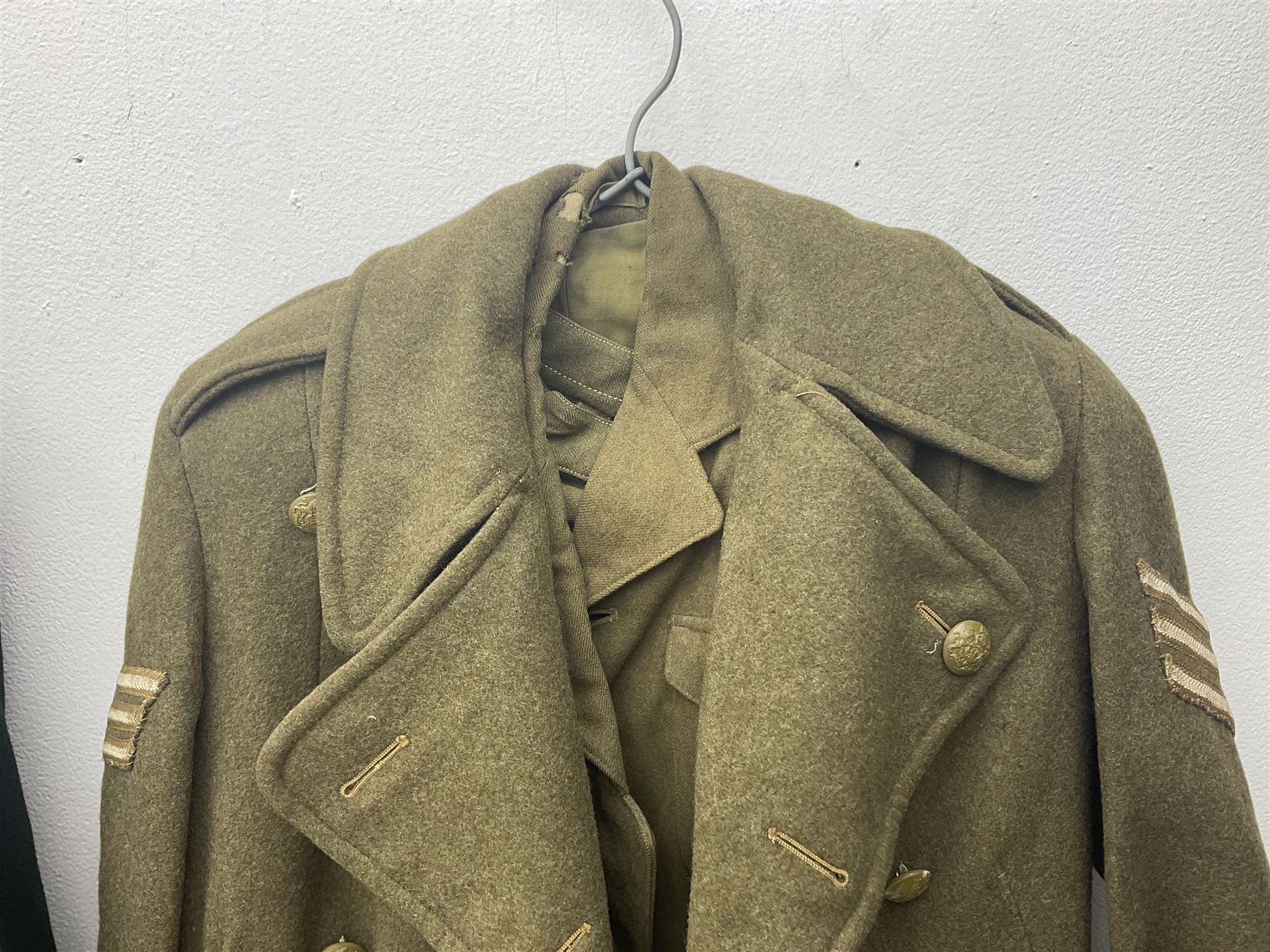 WW2 British female ATS Sergeant's service uniform grouping, consisting of four pocket female pattern service dress tunic with brass ATS shoulder titles and general service buttons; cloth lined interior with the original printed size label dated 1942; the matching khaki service dress skirt; and Greatcoat with size label dated 1945; together with army knitted sleeveless V-neck jumper; WRAC tunic, skirt and overcoat; full length cream and gold thread military evening dress by Hilliers Couture; and four webbing belts