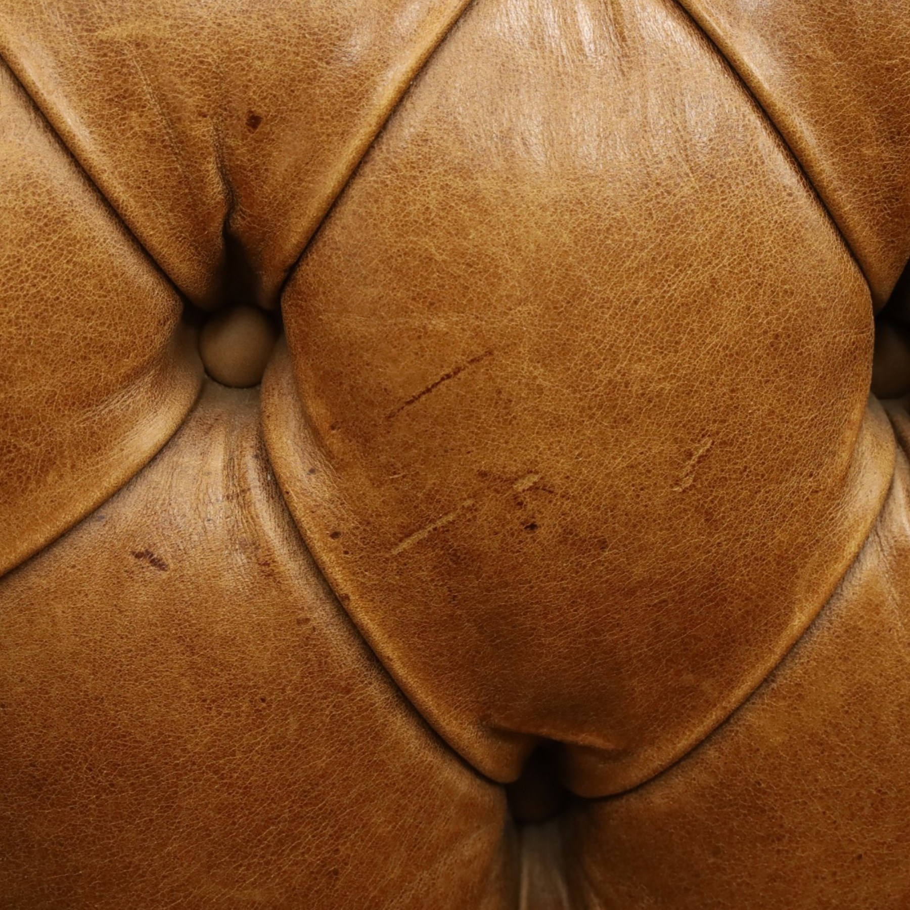Distinctive Chesterfields - traditional shape four seater Chesterfield sofa, the rolled back and arms upholstered in deep-buttoned tan leather with matching loose seat cushions, raised on six turned supprorts