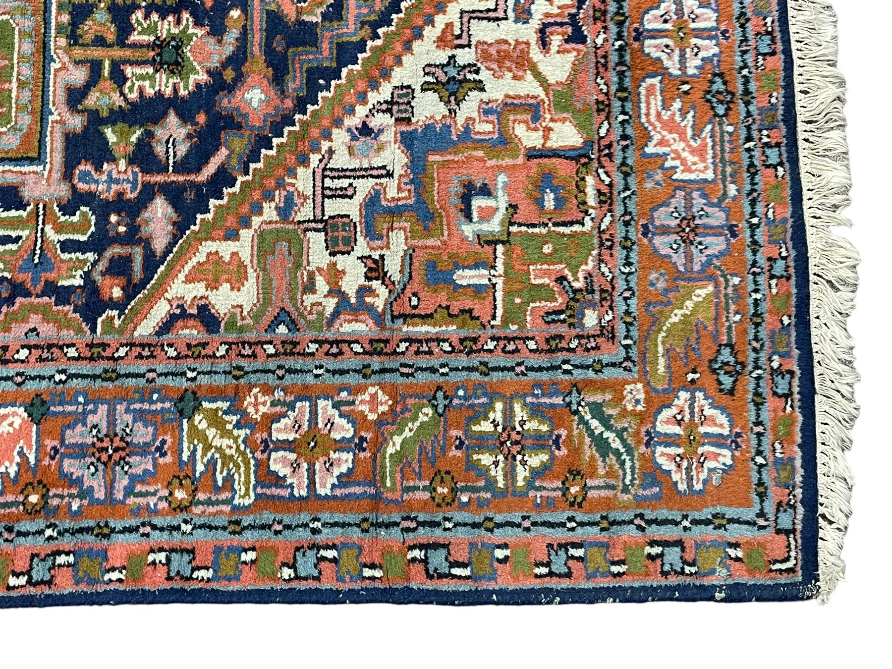 Persian Heriz indigo and rust ground rug, central geometric star medallion decorated with stylised foliate motifs, the border decorated with stylised flower heads