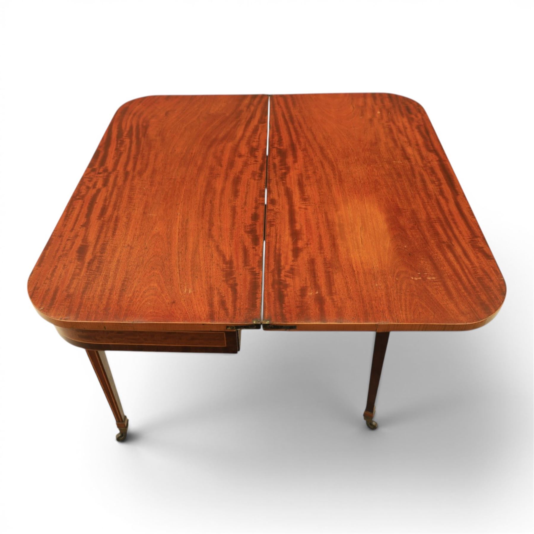 Regency mahogany fold-over tea table, rounded rectangular top with gateleg action, inlaid and crossbanded frieze, raised on squared tapering supports on brass castors