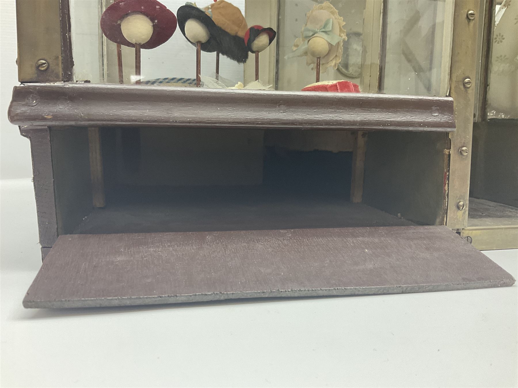 Early 20th century scratch-built wooden hat & gown shop diorama 'Joan', of double-fronted form glazed on three sides with brass and aluminium mounts, rear access apertures and storage under L63cm H45cm D31cm; with small collection of dresses and hats on display stands