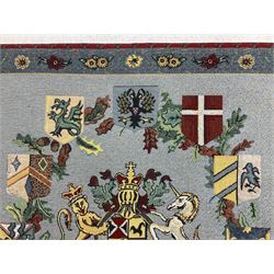 Three tapestries comprising 20th century wool tapestry panel of a medieval nobleman upon a horse with a castle in the distance, together with a smaller tapestry depicting The English Coat of Arms, both hung on rails, and further depicting village scene, largest approx 132cm x 95cm