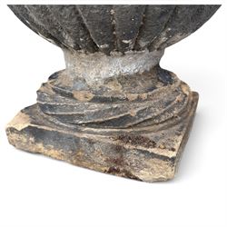 Set of three 19th century weathered carved sandstone garden urns of Neoclassical campana form, the broad everted rim carved with pointed egg-and-dart motifs, above a plain waisted bowl with gadrooned underbelly, on moulded rope-twist socle and square plinth base