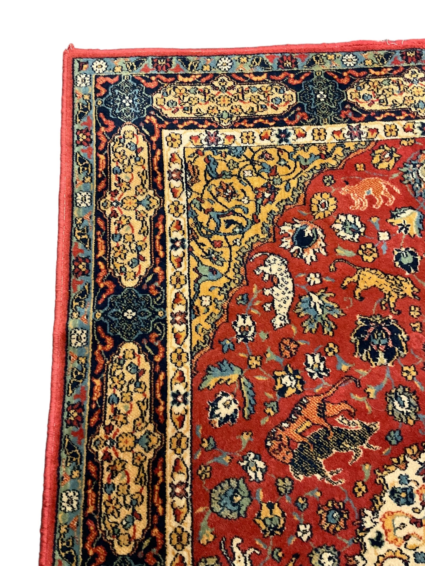 Persian design red ground rug, decorated with plant and animal motifs, the border decorated with floral design panels with guards