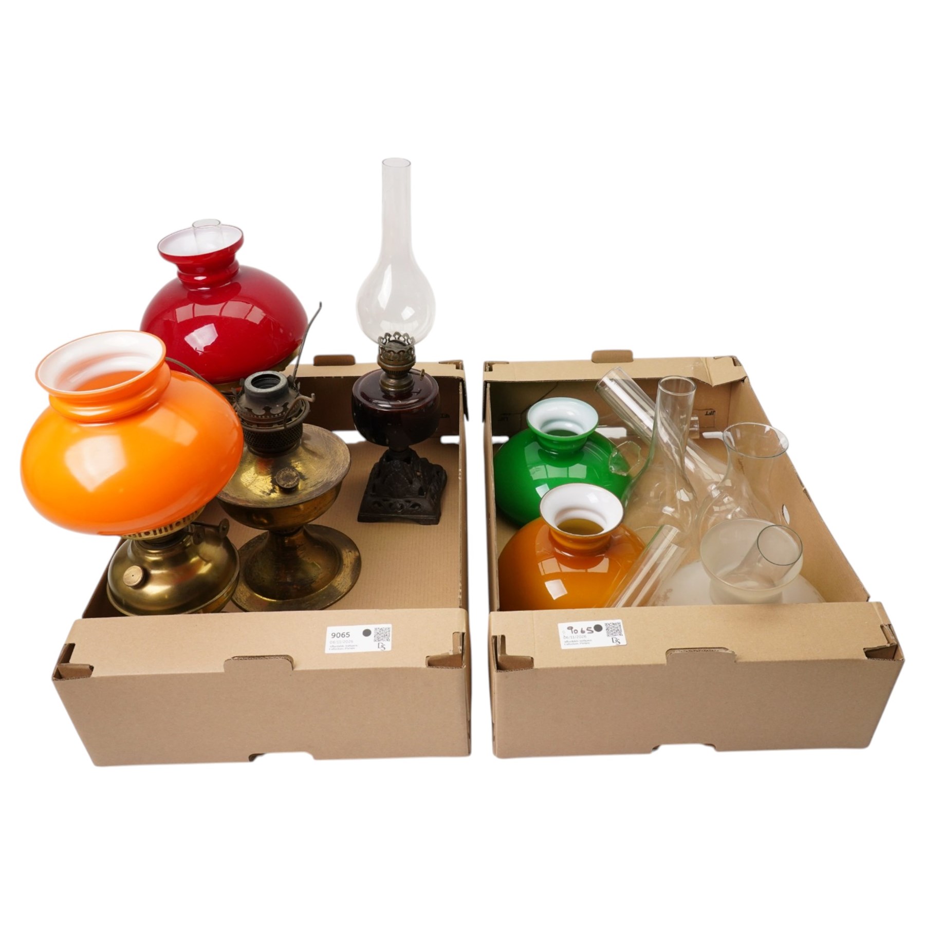 Table oil lamp with red glass reservoir on metal base, three other oil lamps and various shades and chimneys