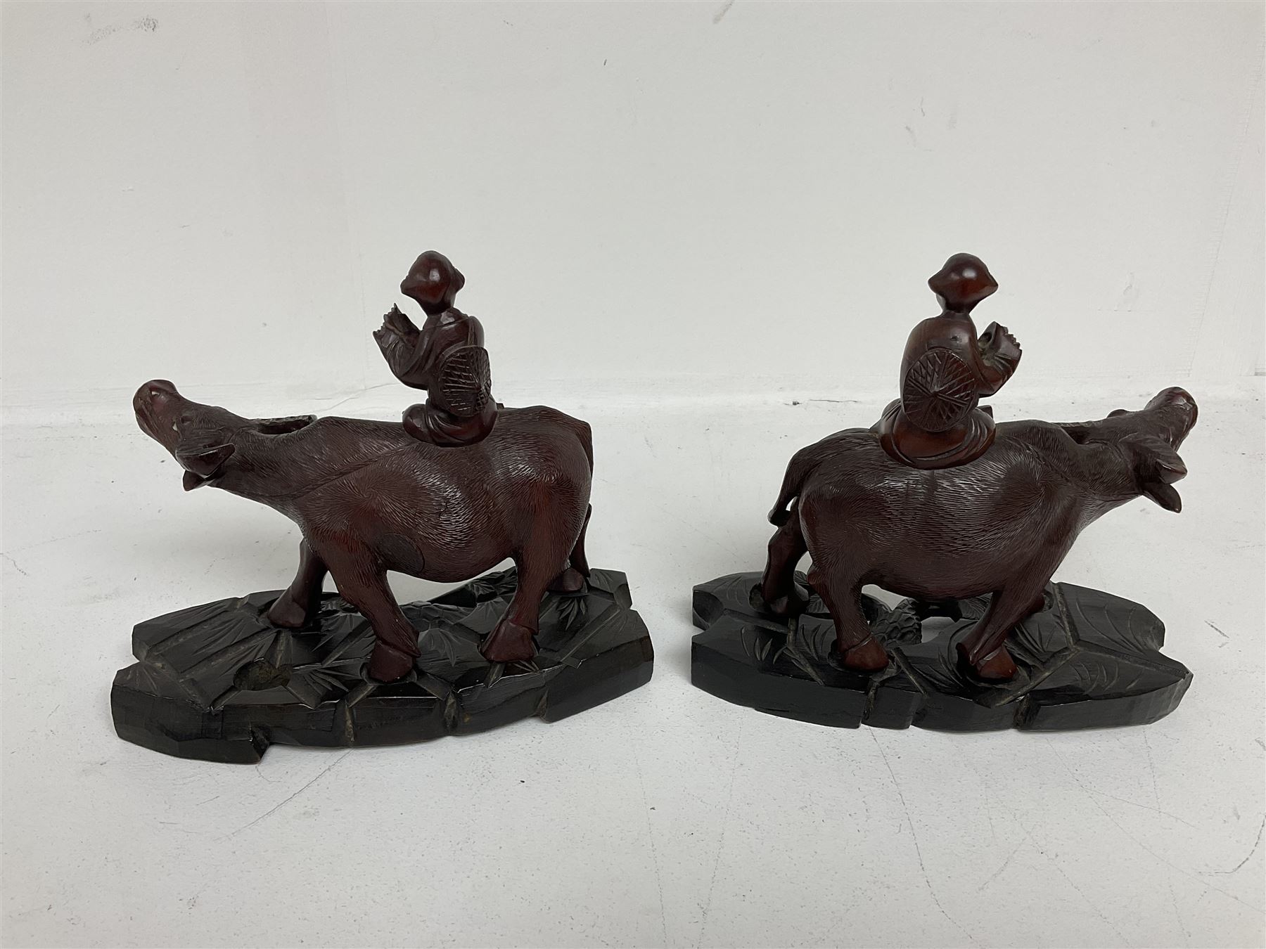 Pair of Chinese hardwood figures of farmers riding water buffalo, on stands, H19cm