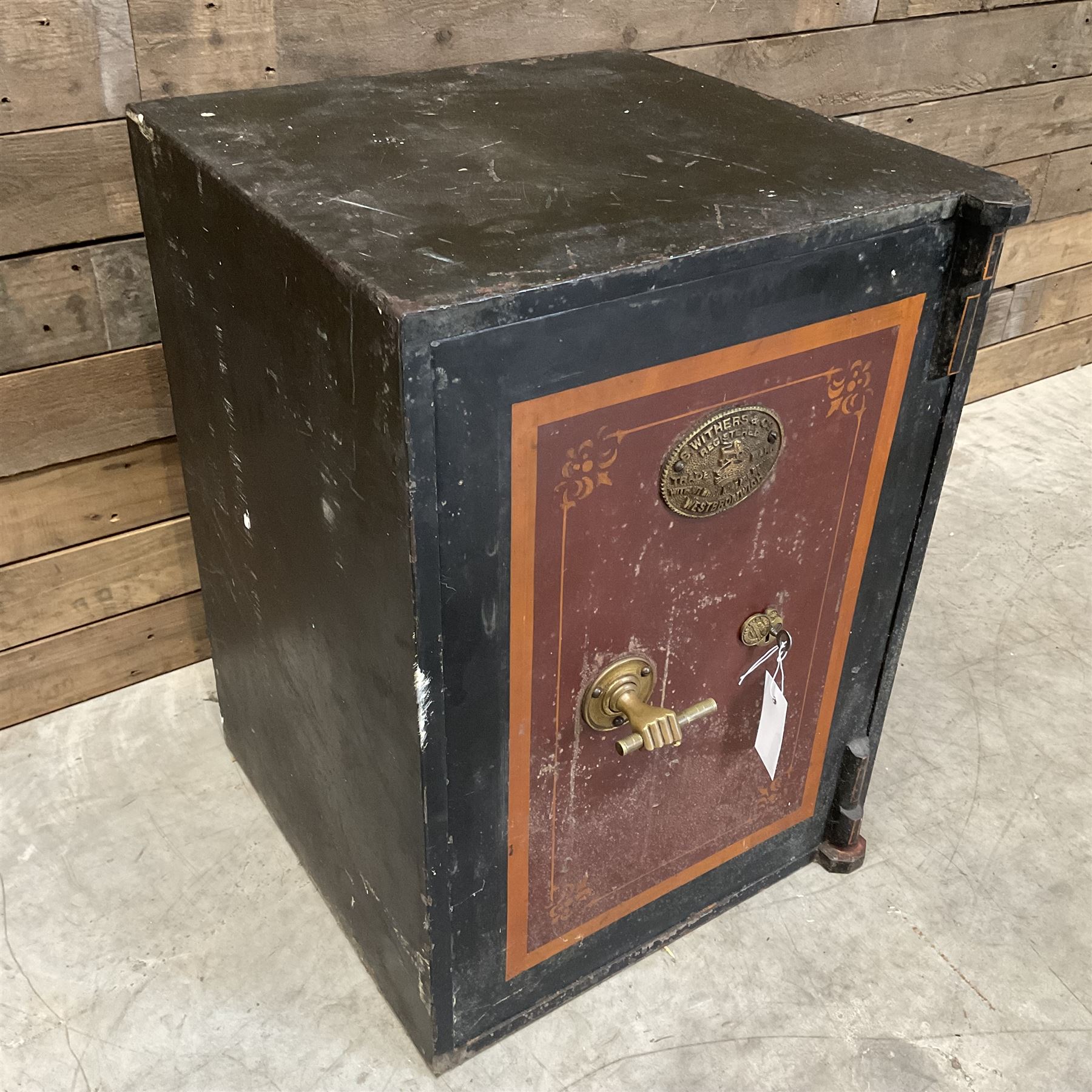 Samuel Withers & Co of West Bromwich - Victorian cast iron safe, the brass handle modelled as a clenched fist, painted in red, orange and black, with key. Ground floor delivery only, no steps.