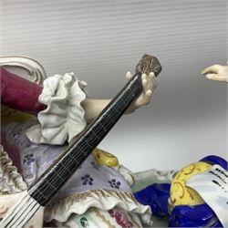 20th century Naples figure group, modelled as a seated female figure playing the lute seated, before a male figure stood holding a sheet of music, each in period dress, upon an oval base with gilt heightened scroll edge, with crowned N mark beneath, H31.5cm L33cm
