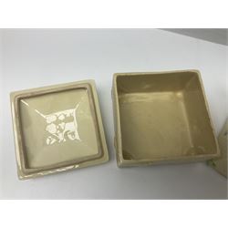 Four square honey boxes with lids,  each decorated with honeycomb pattern and finished with a bee finial