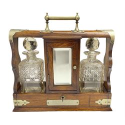 Early 20th century oak tantalus with silver plated mounts and handles, with two recesses, each containing a cut glass decanter, divided by 
a central compartment, the hinged mirrored door opening to reveal two glasses and a shelf, with cribbage board to a drawer below and presentation plaque to body, with key, H36cm W37cm