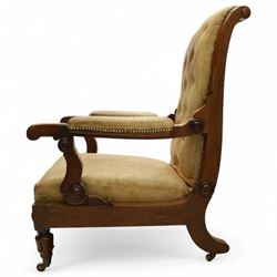 William IV mahogany gentleman's library reclining armchair, leather button upholstered and brass-studded back and seat, above leather-covered arms terminating with carved roundels and foliate scroll-carved ends, underside with brass mechanical trigger reclining lever, the apron with retractable foot rest, supported on lappet carved and turned legs with brass castors, circa 1835