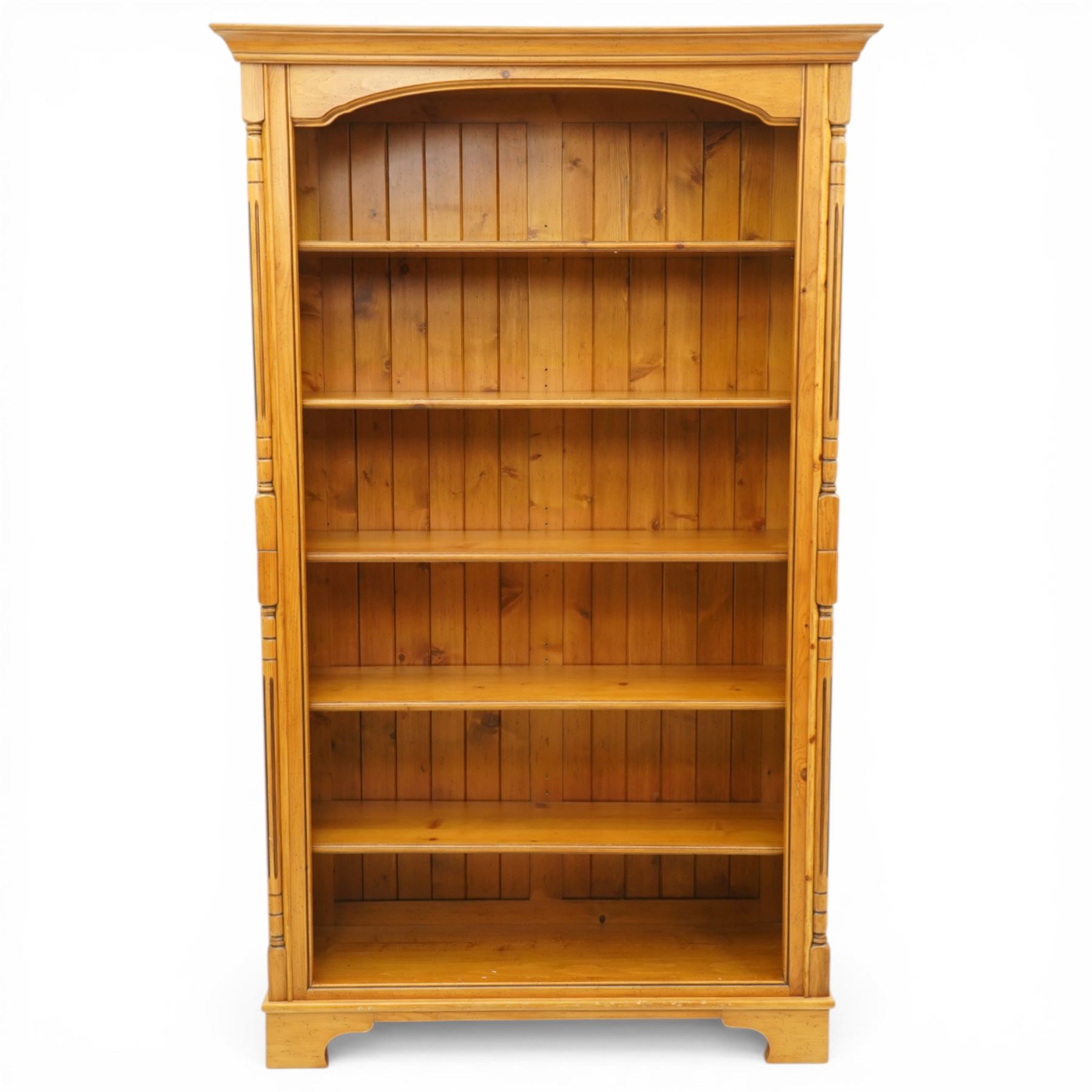 Late 20th century traditional waxed pine open bookcase, moulded cornice above a shaped frieze, open front with fixed shelves and boarded back, flanked by fluted pilasters