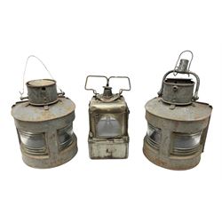 Two WW2 period ship's bow-fronted lamps with grey painted finish, each impressed G.P. Ltd and dated 1943 and 1944; lacking oil burners; one with hinged hanging bracket H28cm excluding bracket; and Lamp Manufacturing & Railway Supplies Ltd Welch patent style lamp of square section with four glazed panels and original oil burner H25cm excluding swing handle (3)