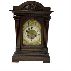 A German carved oak cased mantle clock with a raised pediment, reeded side columns on a stepped plinth with an egg and dart moulding, with a brass dial and silvered chapter ring, Arabic numerals and minute track, non-matching steel hands and subsidiary dials for strike/ silent and pendulum regulation, with an eight-day three train movement striking the quarters on four gong rods and a coiled gong. With pendulum.


