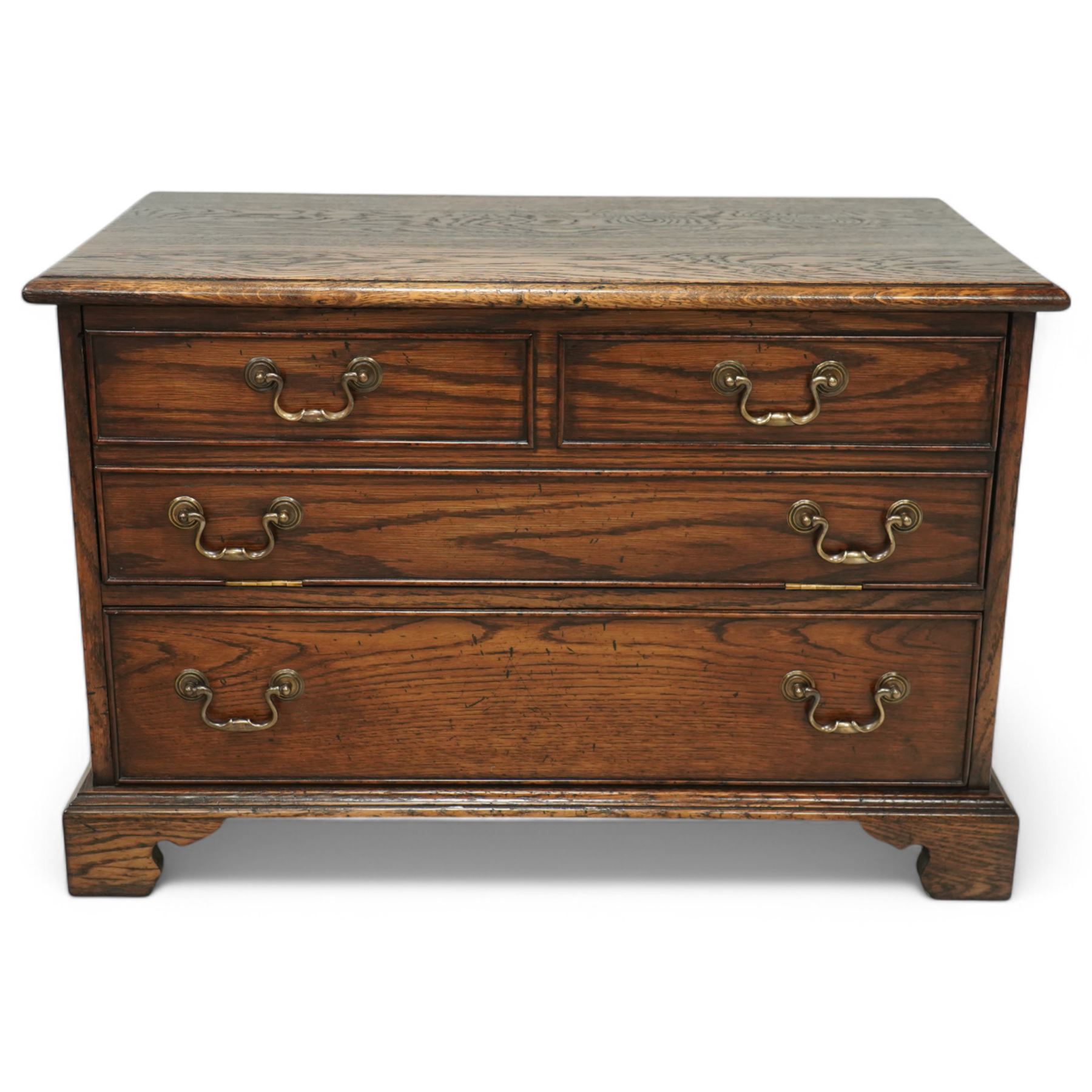 T & G style solid oak television cabinet, rectangular moulded top over two short and two long drawers with brass swing handles, the upper frieze drawer front hinged and fitted with stay to reveal pull-out shelf, open compartment above with circular cable aperture to rear, on bracket feet