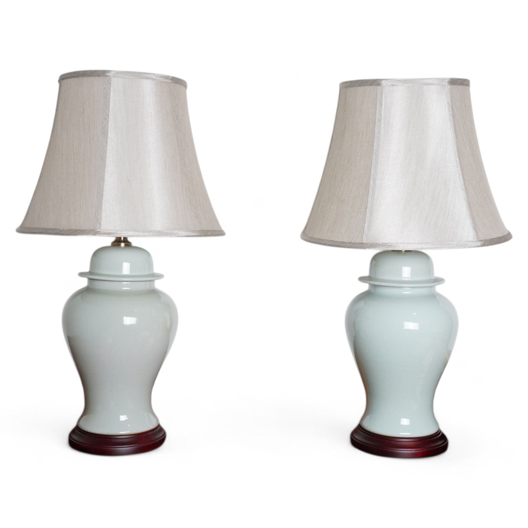 Pair of Chinese porcelain lamps in the form of vases and covers, each decorated with a pale blue crackle glaze, raised upon circular hardwood base, H68cm including shades