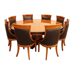  Empire style ebonised banded ash curl pedestal dining table, circular top with urn and fan inlaid panels on tapering square support with  outsplayed scroll feet, D190cm, H75cm and a set of eight dining chairs, brass nail upholstered with curved backs on sabre legs, W52cm, (9)  
