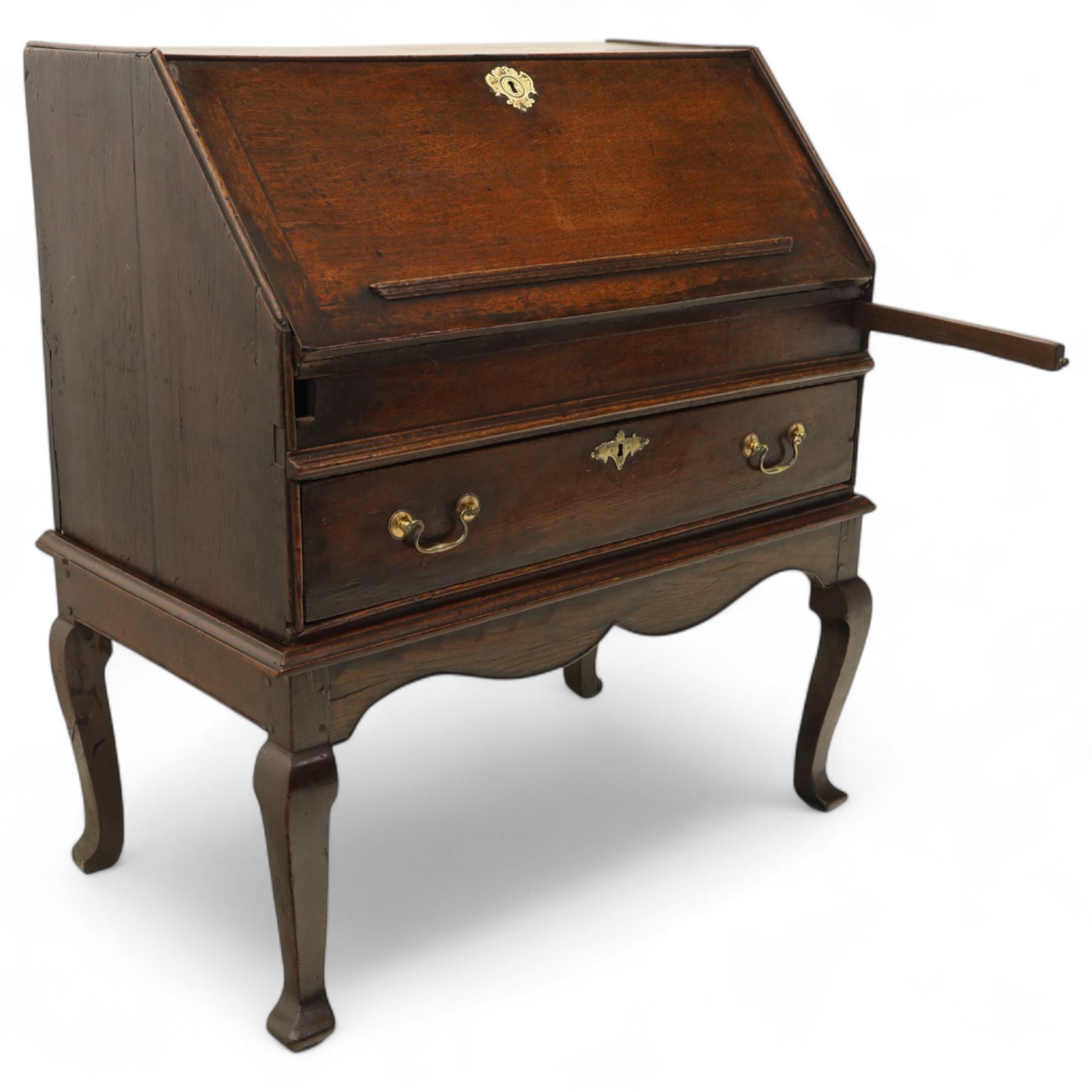 Early 18th century George I oak bureau on original stand, the fall front enclosing an arrangement of correspondence drawers and pigeonholes over central well, fitted with single long drawer below, the shaped apron over cabriole supports with pad feet