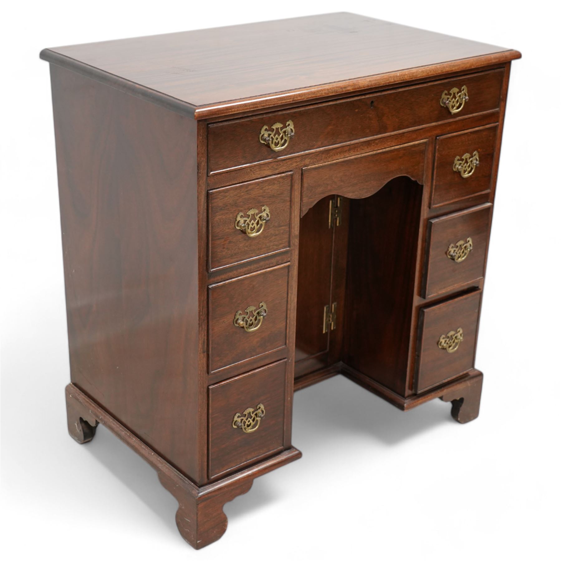 Georgian design mahogany kneehole desk, moulded rectangular top over single drawer, shaped frieze drawer and six short drawers, recessed kneehole with cupboard, on bracket feet