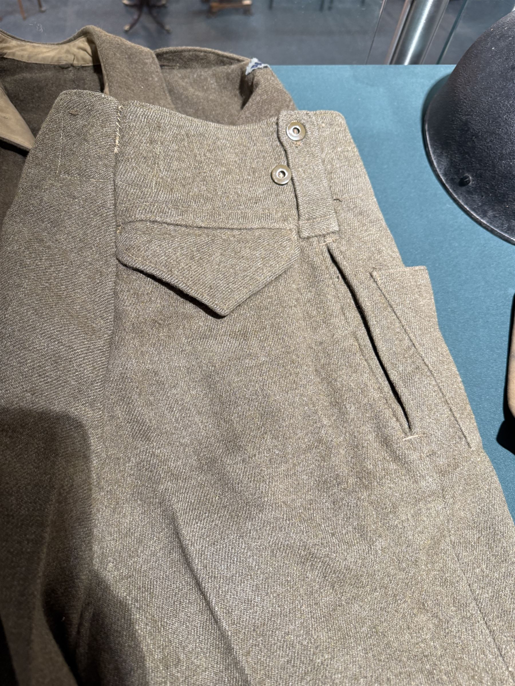 WWII British parachute regiment battle dress uniform, the jacket with shoulder title and Pegasus formation badge to the left arm, shoulder title, Pegasus formation badge and cloth wings to the right, size 3 dated 1943, the trousers size 3 dated 1945 