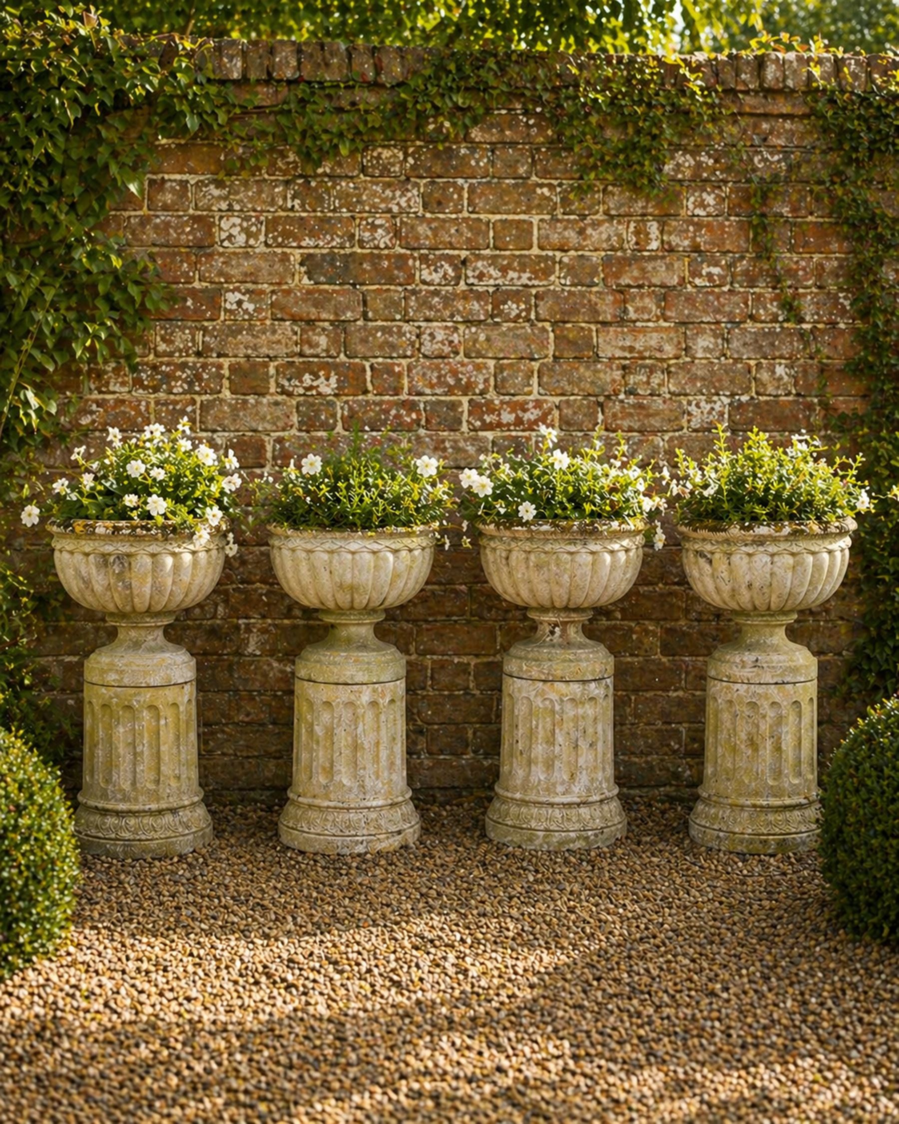 Four 20th century good quality weathered cast stone pedestal urns, circular lobed bowls with rope twist and lattice border, raised on squat base with fluted columns