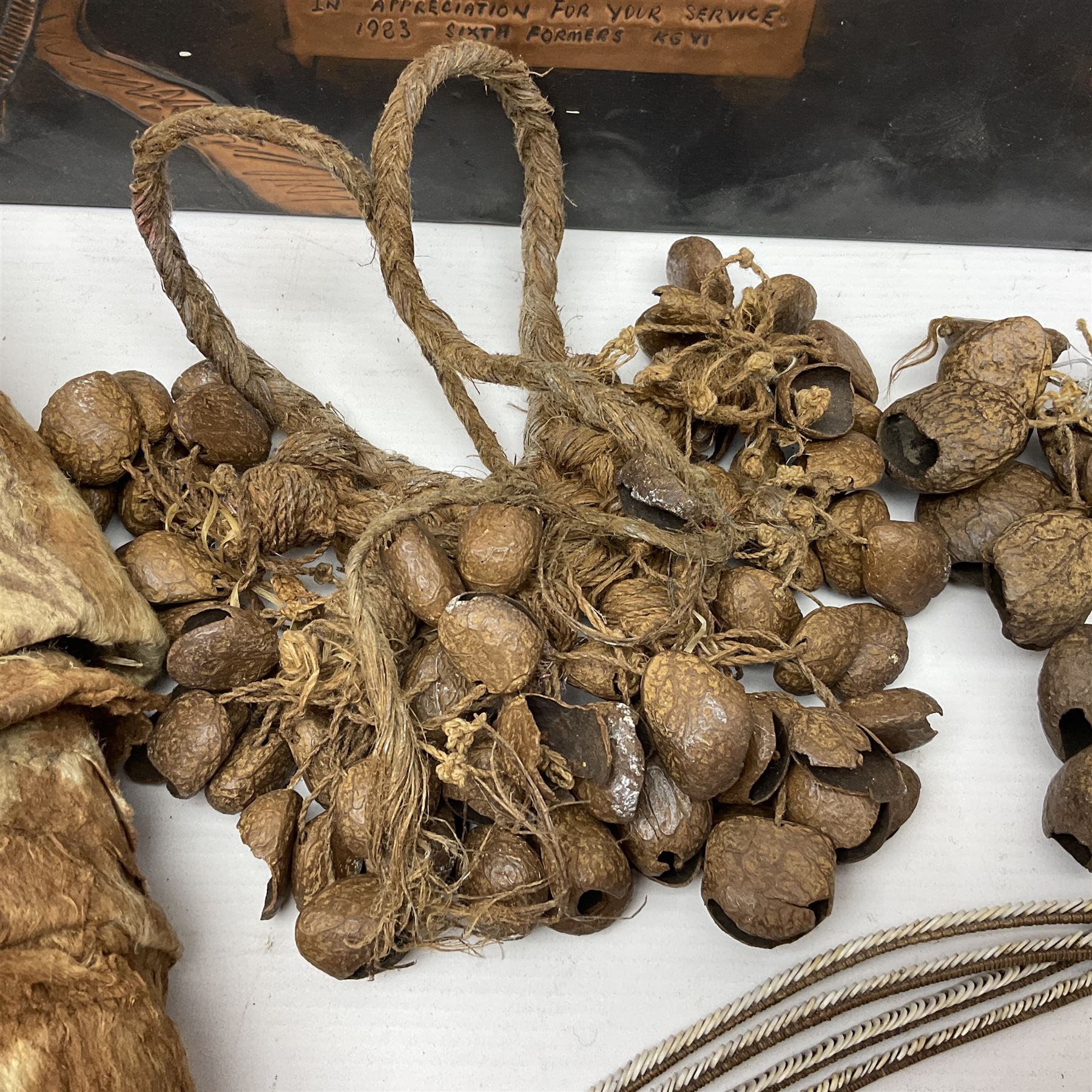 Collection of traditional necklaces from the Solomon Islands, including shell and boar tusk examples, together with a carved canoe prow, with mother of pearl eyes, painted cow hide and a copper plaque, depicting the Solomon Islands, with presentation engraving