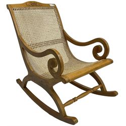 Late 20th century teak framed plantation style rocking chair, cresting rail carved with two elephants with upraised trunks, cane back and seat with scrolled arm terminals, rocker base united by turned stretcher