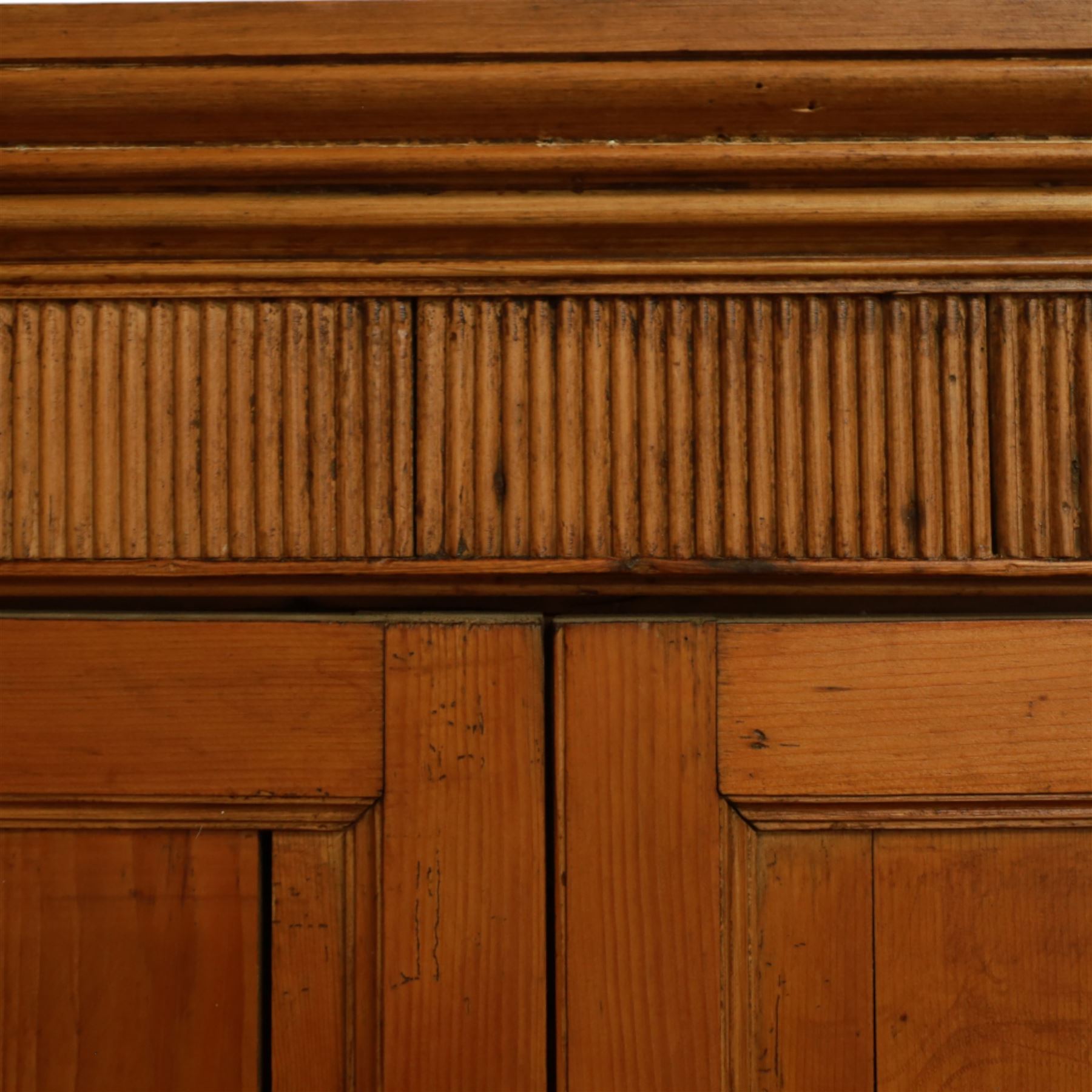 Victorian stripped pine kitchen cupboard, of rectangular form with fluted cornice and top section with two panelled cupboard doors revealing painted shelved interior, middle with two drawers with turned knob handles and brass cup handles, base section with two panelled cupboards, raised on shaped bracket feet 