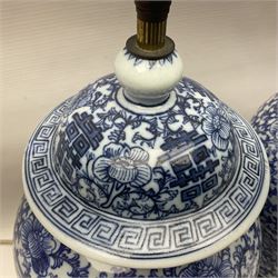 Pair of 20th century Chinese blue and white jars and covers, converted to table lamps, each of baluster form with domed cover, decorated with auspicious symbols, flower heads and training vines, upon turned circular wooden base, including fittings overall H43cm