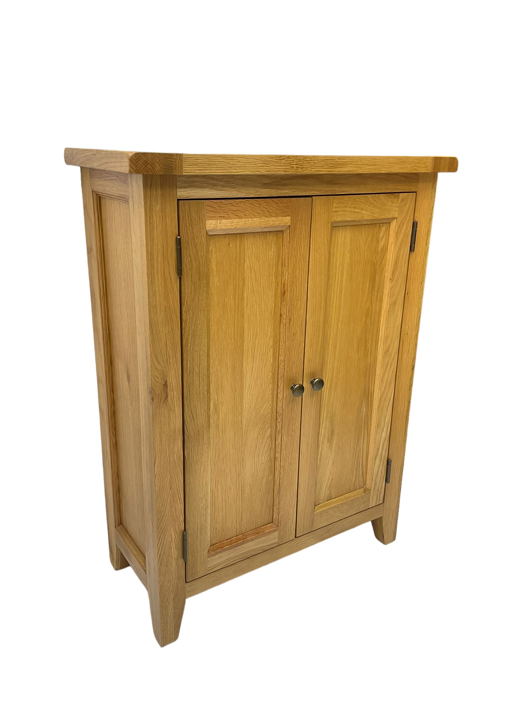 Solid light oak cupboard, fitted with two panelled doors enclosing two shelves, on tapered feet