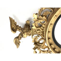 Large Regency carved wood and gesso circular convex mirror, eagle pediment on platform flanked by acanthus leaf scrolls, moulded surround and ebonised slip