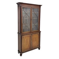 Late Regency mahogany bookcase on cupboard, projecting cornice over two moulded astragal glazed doors, the left-door hinges to allow the right-hand door to slide, central slide over double panelled cupboard, flanked by reeded uprights, on turned a lobe carved feet