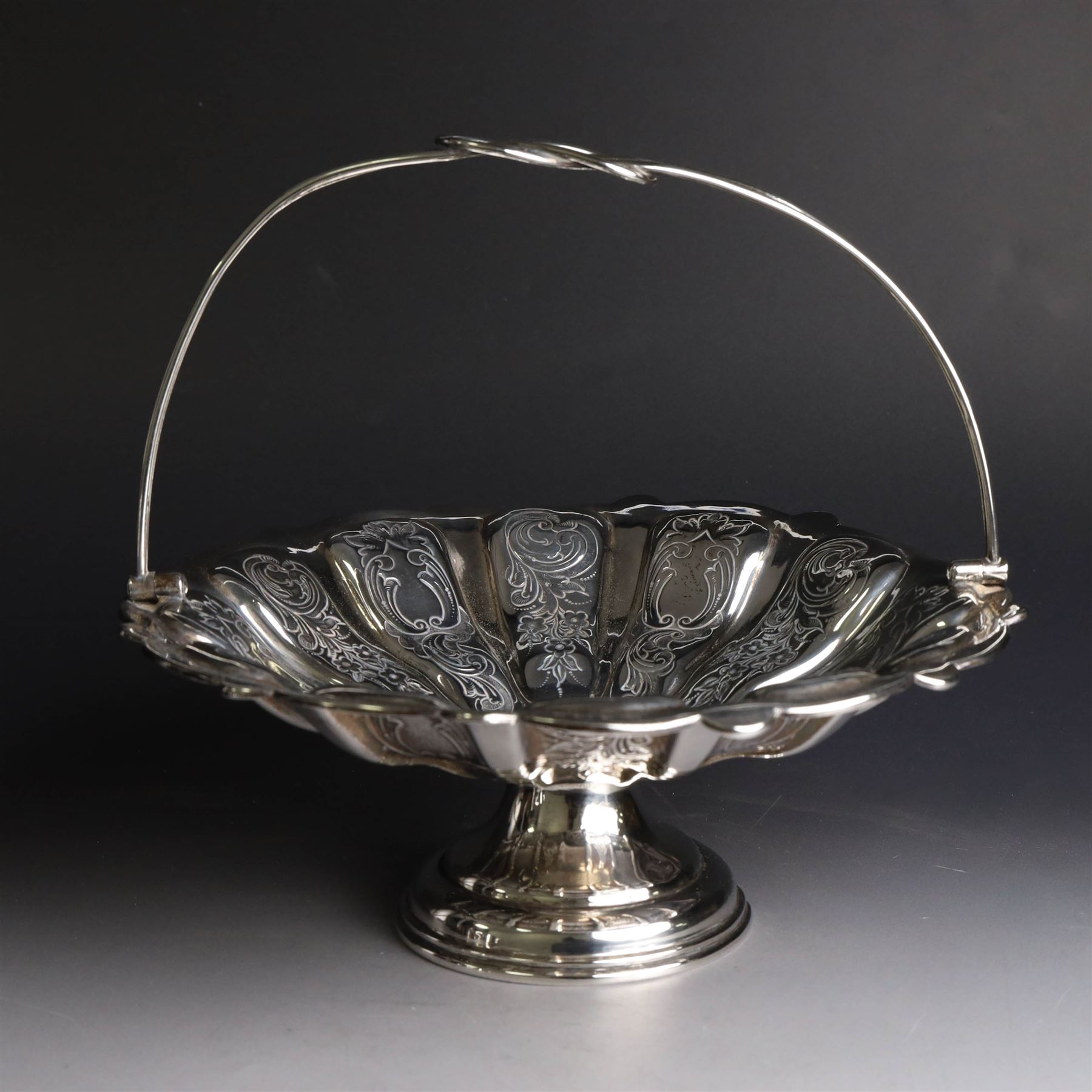 Edwardian silver swing handled basket, of circular form with shaped rim and engraved floral and foliate decoration, with know design swing handle and upon circular stepped pedestal, hallmarked J Sherwood & Sons, Birmingham 1901, H9cm, D22cm