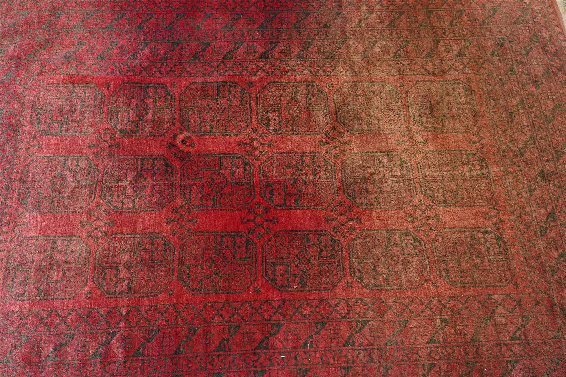 Afghan crimson ground Bokhara rug, the field with three rows of repeating Gul motifs, within six concentric guard bands decorated with repeating geometric patterns