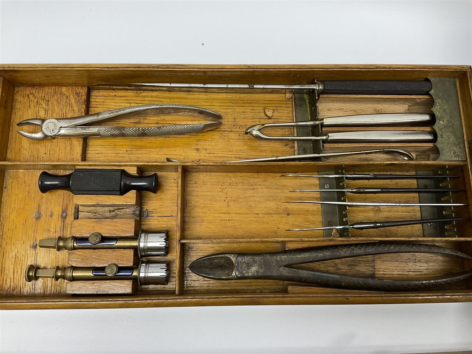 Naval doctor's surgical instruments, contained in a converted brass bound oak pistol box, the hinged lid opening to reveal two removable fitted trays, containing 19th century and later saws, scalpels, tweezers etc